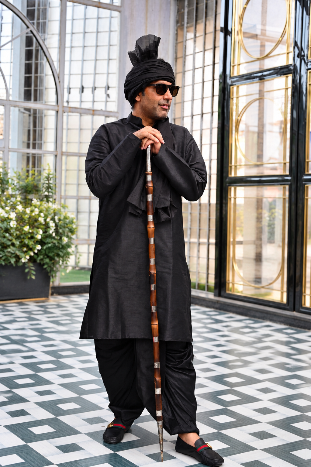 Gaurhav Nagar in a black traditional outfit holding a staff